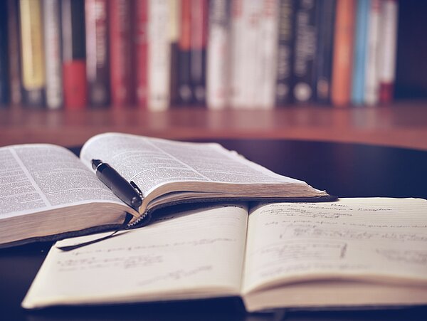 Promovieren Ein Buch und ein Notizheft liegen versetzt aufeinander