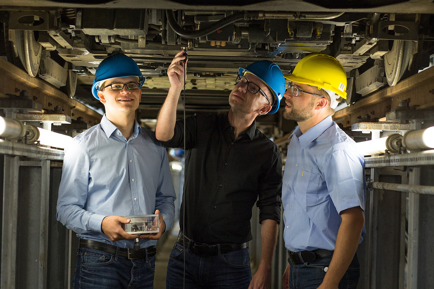 Traincon Maik Wolf, Professor Mathias Rudolph und Robert Richter vom LVB-Tochterunternehmen IFTEC stehen in einer Straßenbahnwartungsgrube und testen das entwickelte System.