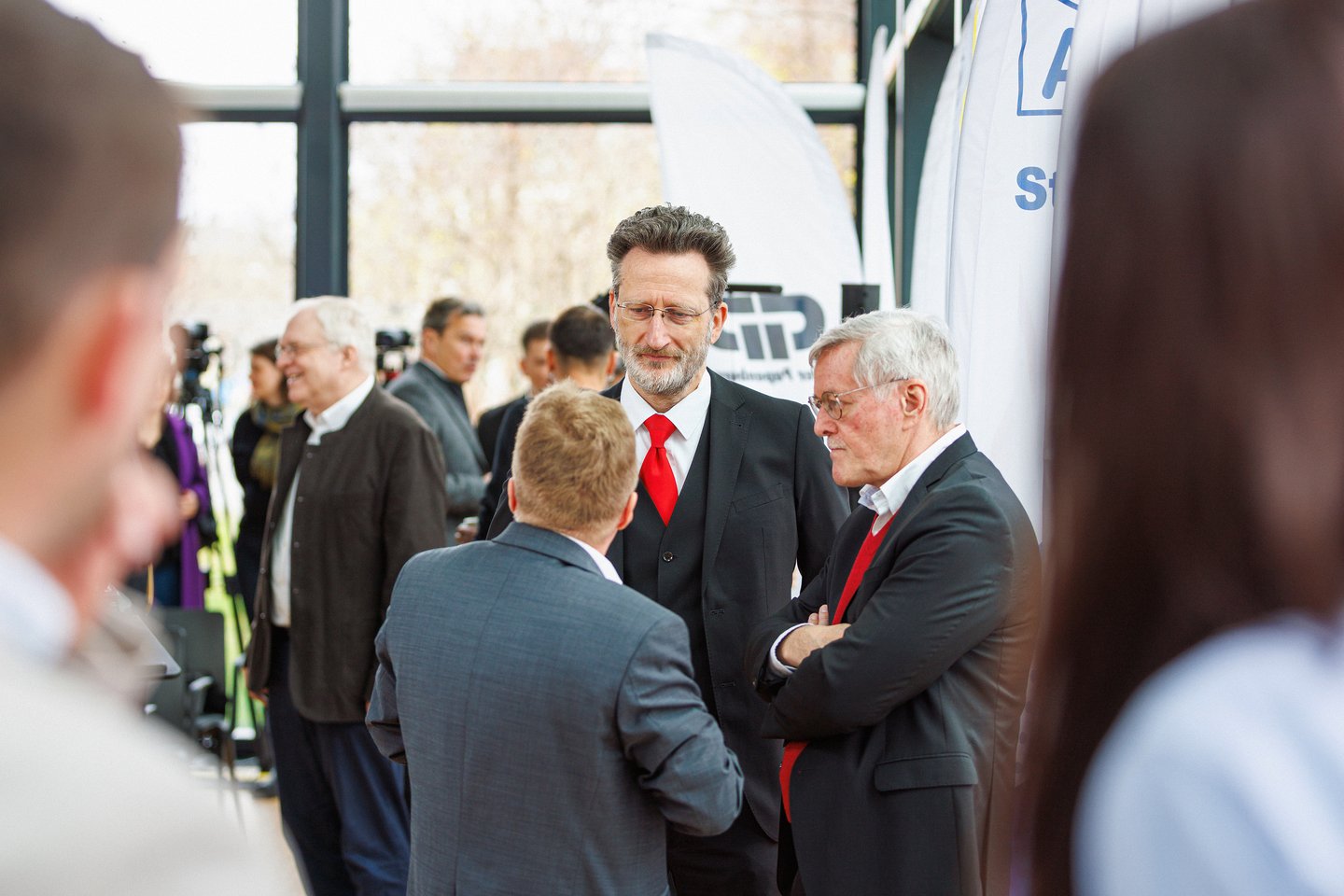 Drei Männer in Publikum reden miteinander