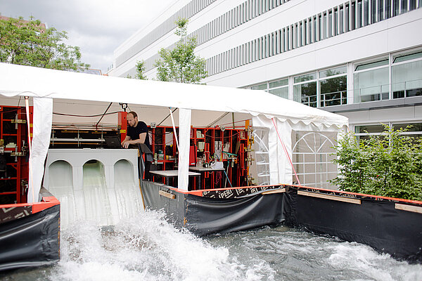 Miniatur-Modell der Talsperre Lehnmühle (Foto: Robert Weinhold/HTWK Leipzig) Unter einem langen Pavillon sind im Freien viele Geräte des Wasserbaulabors aufgebaut. In der Mitte ist eine Talsperre errichtet, durch die Wasser fließt